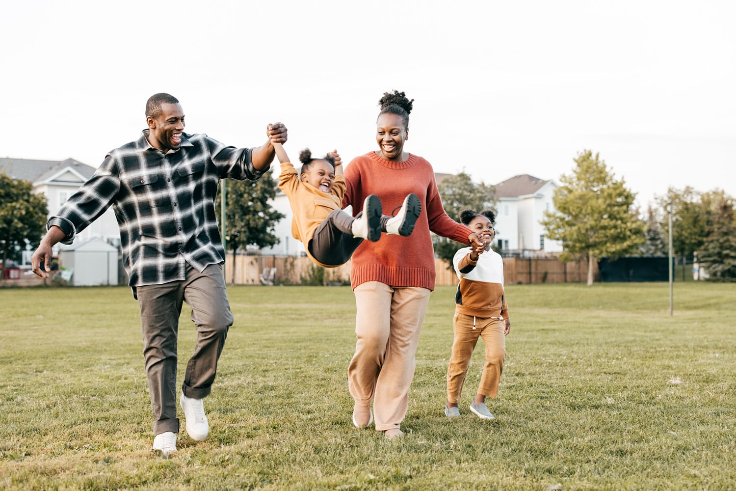 A mom, dad, and two kids play together outside.