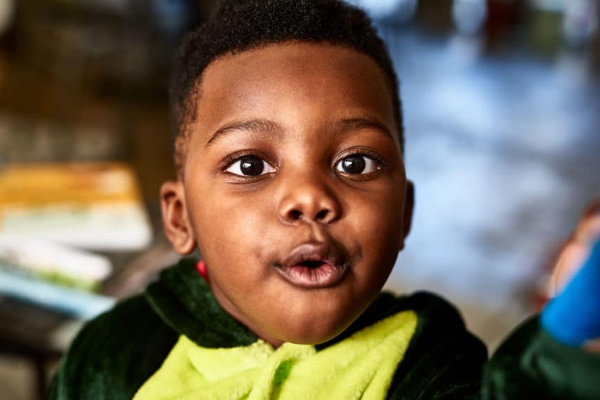 Close up portrait of toddler with open mouth looking at camera