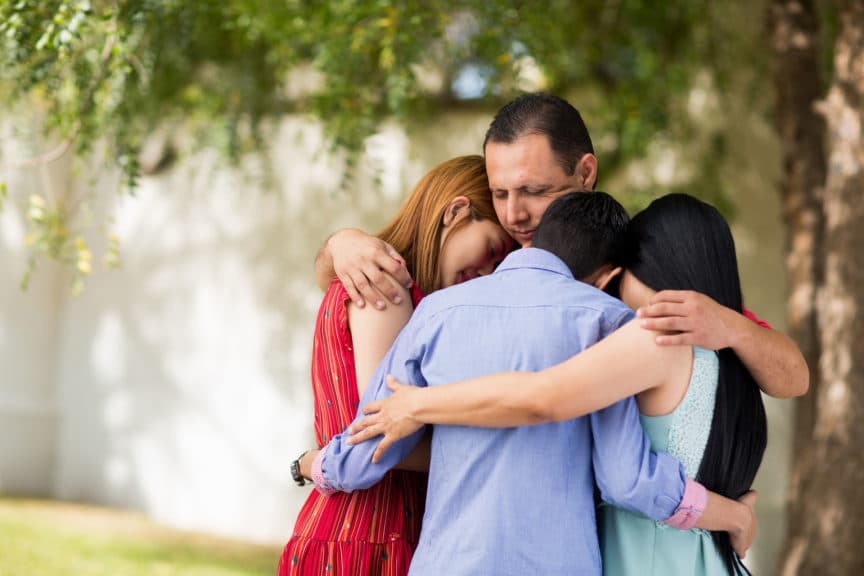family praying and embracing outdoors
