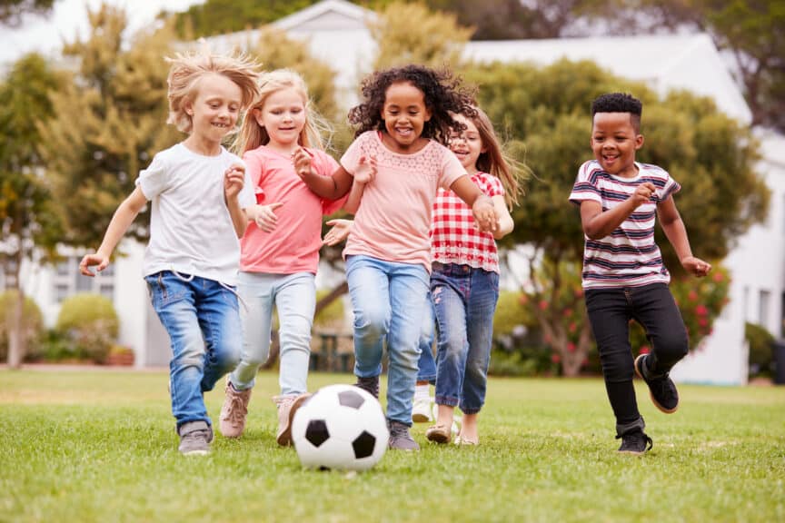 Group Of Children Playing soccer With Friends In Park