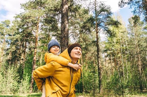 father carrying son on his back on a hike